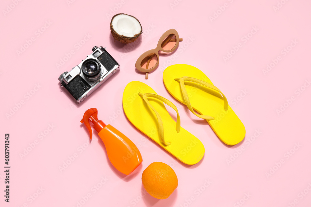 Beach accessories with photo camera and fruits on pink background