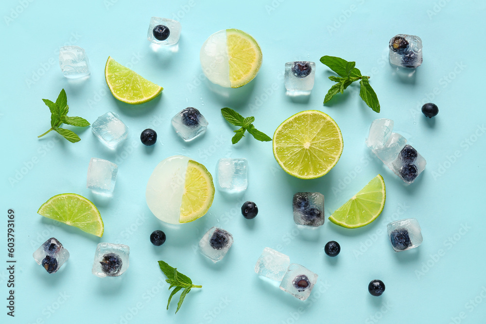 Fresh blueberry frozen in ice cubes with mint and lime on blue background