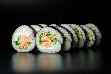 Rolls with tuna, cream cheese, cucumber, rice and nori, isolated on black