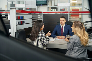 Two young women and a man in the office area