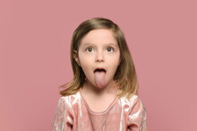 Funny Little Girl Showing Her Tongue On Pink Background
