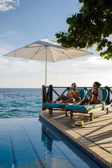 Wall Mural - Curacao, couple man and woman mid age relaxing by the swimming pool during a vacation in the Caribbean