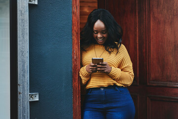 Canvas Print - Door, phone and woman on social media, texting and happy while reading message in front of house. Smartphone, influencer and african female online for blog, networking or accommodation app review