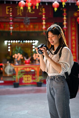 Wall Mural - A female tourist checking photos on her camera, visiting a Chinese temple in the old town