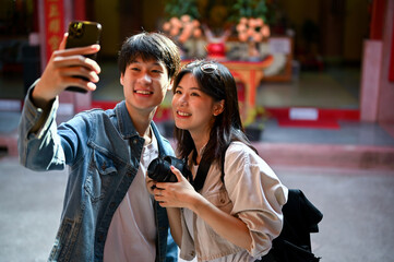 Wall Mural - A tourist couple taking their pictures with a smartphone while visiting a Chinese temple
