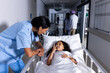 © Wavebreak Media - Biracial female doctor and smiling girl patient in bed talking in corridor at hospital