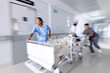 © Wavebreak Media - Diverse doctors urgently pushing patient lying in bed in corridor at hospital