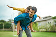 © Camerene P/peopleimages.com - Love, children and a son on back of his dad outdoor in the garden to fly like an airplane while bonding together. Family, kids and a father carrying his male child while playing a game in the yard