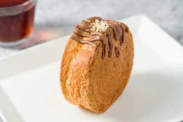 Chocolate New York roll or round croissant with tea on stone table