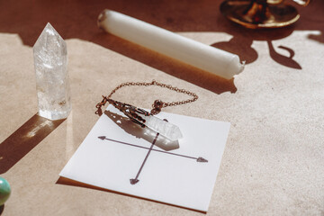 Gemstones for esoteric spiritual practice. Rock crystal pendulum on the table. Divination with a pendulum.