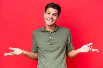 Wall Mural - Young caucasian handsome man isolated on red background happy and smiling