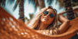 jeune femme blonde avec lunettes de soleil étendue dans un hamac sur la plage avec palmiers