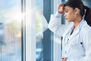 Stress, thinking and doctor woman by window with worry, anxiety and tired with headache in clinic. Healthcare, mental health and sad female health worker stressed, depressed and burnout in hospital