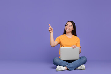 Canvas Print - Smiling young woman with laptop on lilac background, space for text