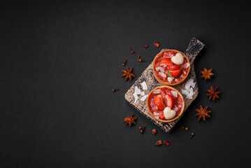 Delicious fresh sweet tartlets with strawberries and coconut flakes