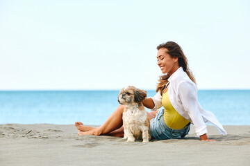 Young happy woman spending summer day on beach with her dog.