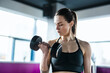 © pikselstock - Young woman exercising with dumbbells in a health club