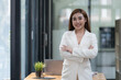 © Songsak C - Confident Asian businesswoman arms crossed thinking of new ideas at the office. Looking at the camera.