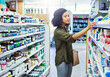 © Tamani Chithambo/peopleimages.com - Pharmacy, shopping and woman search for medicine and product in a retail store. Pharmaceutical, drugs and pills with a African female person looking at box for ingredients and information in shop