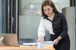 © Songsak C - Asian businesswoman arranging documents on her desk.