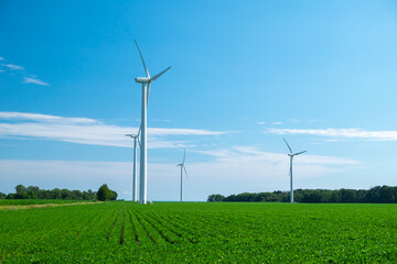 Close view of onshore horizontal axis wind turbine (windmill) in green field, deep blue sky, sunny day. Ontario Canada. Replenishable, green, renewable, alternative energy and natural sources concept.