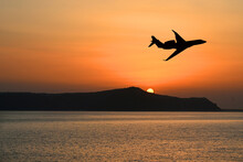 Silhouette Of A Private Executive Jet Flying Over An Island At Sunset. Luxury Travel Concept. Copy Space. No People.