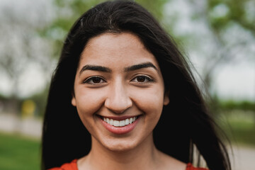 happy young indian woman smiling on camera at city park