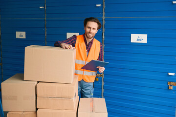 Wall Mural - Young man in work clothes with boxes into warehouse with self storage unit