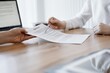 © rogerphoto - Businesswoman lawyer pointing into contract special points admitting something for colleague or client at the wooden desk in office. Business people teamwork and partnership, meeting concept.