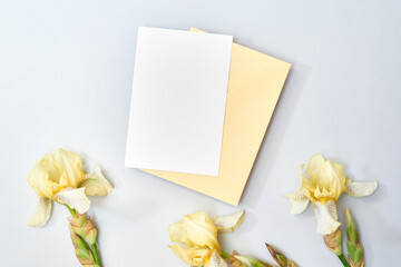 Wall Mural - mockup white greeting card and envelope with yellow irises on a light background