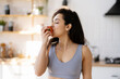 © Maria Vitkovska - Beautiful smiling woman biting apple standing in modern kitchen