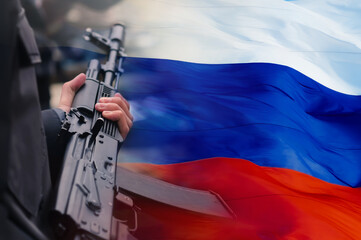 Russian assault rifle in the hands of a Russian soldier against the background of the flag of the Russian Federation. The concept of mobilization and defense of the motherland. Selective focus