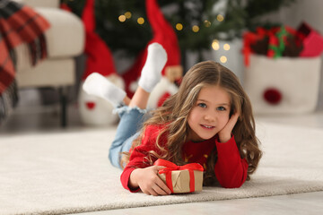 Sticker - Happy girl lying on soft carpet with Christmas gift at home