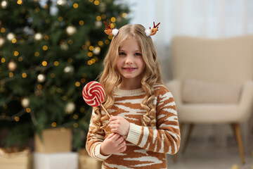 Canvas Print - Portrait of cute girl with lollipop near Christmas tree at home