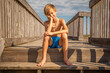 Cute blonde barefoot beach boy sitting on wooden steps
