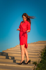 Wall Mural - Portrait of a young beautiful girl in a red dress outdoors in summer.