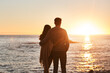 © Emil L/peopleimages.com - Sunset, beach and back of couple hug in evening on holiday, summer vacation and weekend by ocean. Nature, love and man and woman embrace, hugging and relax for bonding, quality time and peace by sea