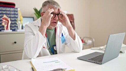 Wall Mural - Middle age grey-haired man doctor stressed working at clinic