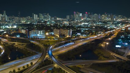 Wall Mural - Aerial view of american highway junction at night with fast driving vehicles in Miami, Florida. Time lapse of USA transportation infrastructure