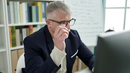 Sticker - Middle age grey-haired man teacher using computer stressed at university classroom