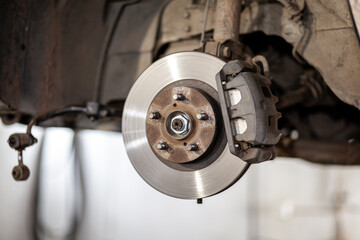 Poster - Disc brake of the vehicle for repair, in process of new tire replacement. Car brake repairing in garage.Suspension of car for maintenance brakes and shock absorber systems. Replacement of brake pads.