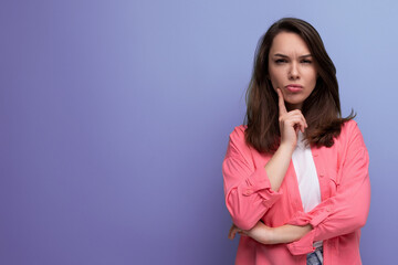 Canvas Print - portrait of a well-groomed european young black-haired woman with shoulder-length hair in a pink shirt on a studio background with copy space