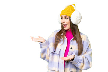 Canvas Print - Young woman wearing winter muffs over isolated chroma key background with surprise facial expression