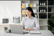 © laddawan - Young beautiful woman typing on tablet and laptop while sitting at the working wooden table office.
