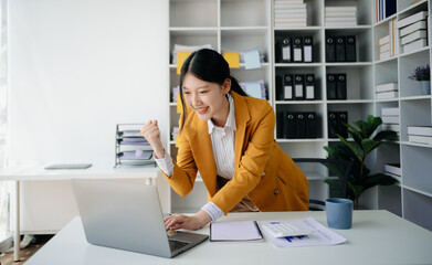 Asian business woman are delighted and happy with the work they do on their tablet, laptop and taking notes at office...