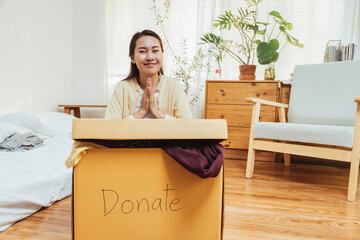 Wall Mural - volunteer asian woman putting unused clothes into cardboard boxes for donation and charity. Reuse, recycle, renewable and sustainability concept.