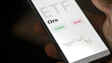 An Investor Analyzing An Etf Fund. ETF Text In Spanish : Gold, Buy, Sell.