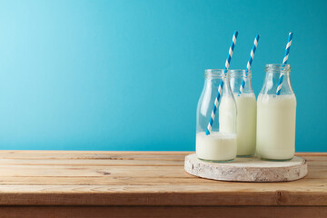 Wall Mural - Milk bottles on wooden table over blue background