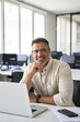 © Stock 4 You - Vertical portrait of mature Indian or Latin business man ceo at table with laptop computer, working in modern office. Middle-age Hispanic smiling handsome businessman entrepreneur looking at camera.