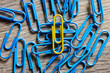 The yellow paper clip stands out among the group of blue paper clips. Leader concept, think differently.